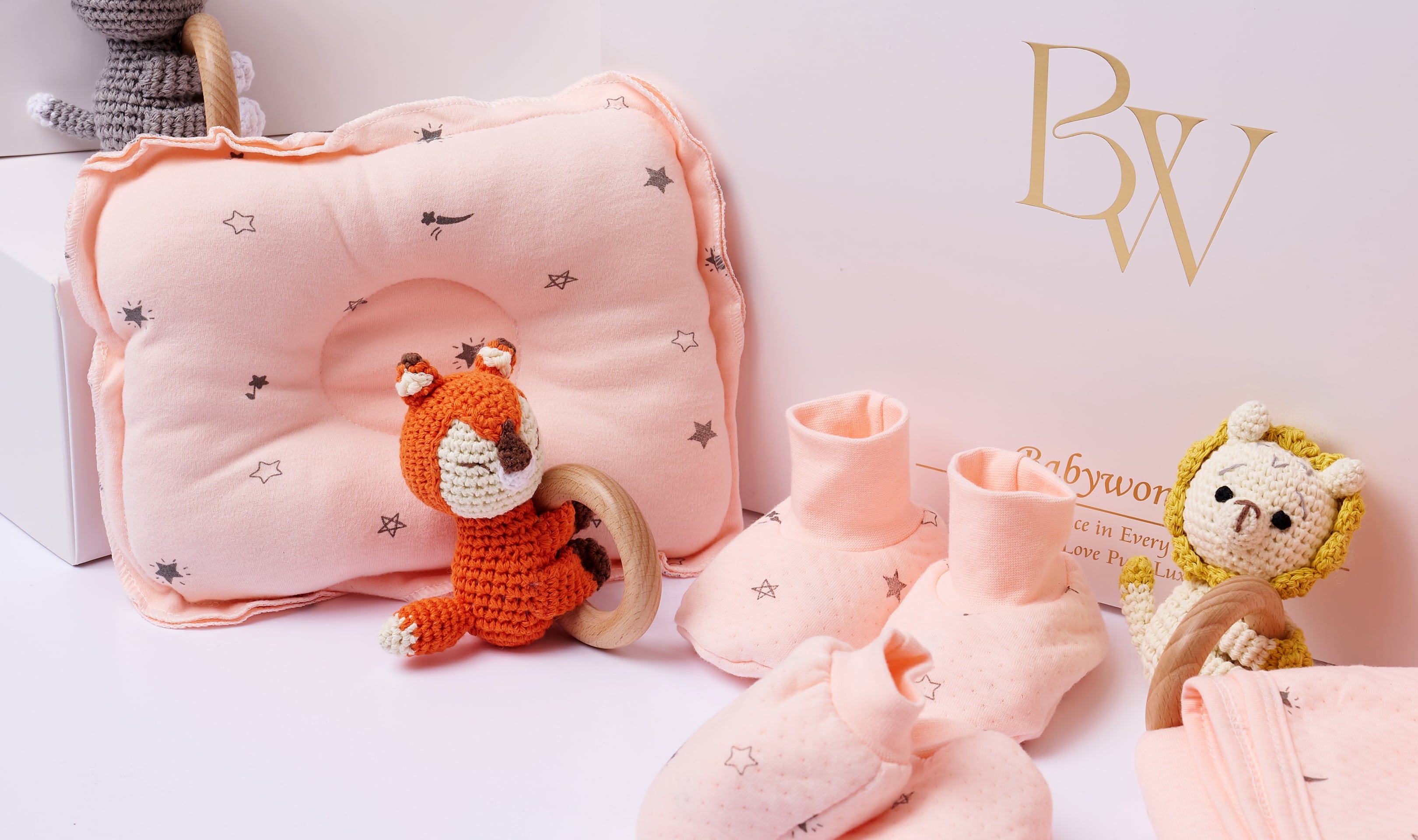 Custom baby gift set in soft pink tones, featuring baby socks, plush toys, a blanket, and a personalised embroidered pouch.