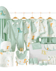 Green dinosaur baby gift set with bodysuit, bibs, socks, gloves, towel, pillow, and wrap arranged in a gift box