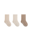 Three pairs of socks in beige, white, and brown on a white background