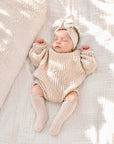 Baby wearing ribbed knit knee-high baby socks in soft cotton with cosy neutral newborn outfit and minimalist nursery style