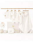 Luxury baby clothing gift set with newborn essentials including onesies, blanket, bib, and plush toy