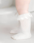 Baby wearing white lace knee-high cotton socks, breathable and soft toddler ruffle socks