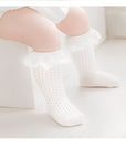 Toddler girl wearing white lace cotton knee-high socks with frilly trim, soft breathable design