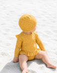 Baby in yellow polka dot long sleeve swimsuit sitting on beach sand, lightweight breathable toddler swimwear for summer