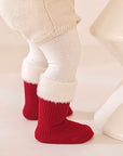 Baby wearing red Christmas socks with soft white cuffs, festive and warm winter look.