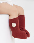 Baby wearing red cotton socks with white pom pom accent, cozy and soft for Christmas season.