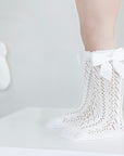 White baby lace knee-high socks with bow, breathable cotton knit worn by infant girl