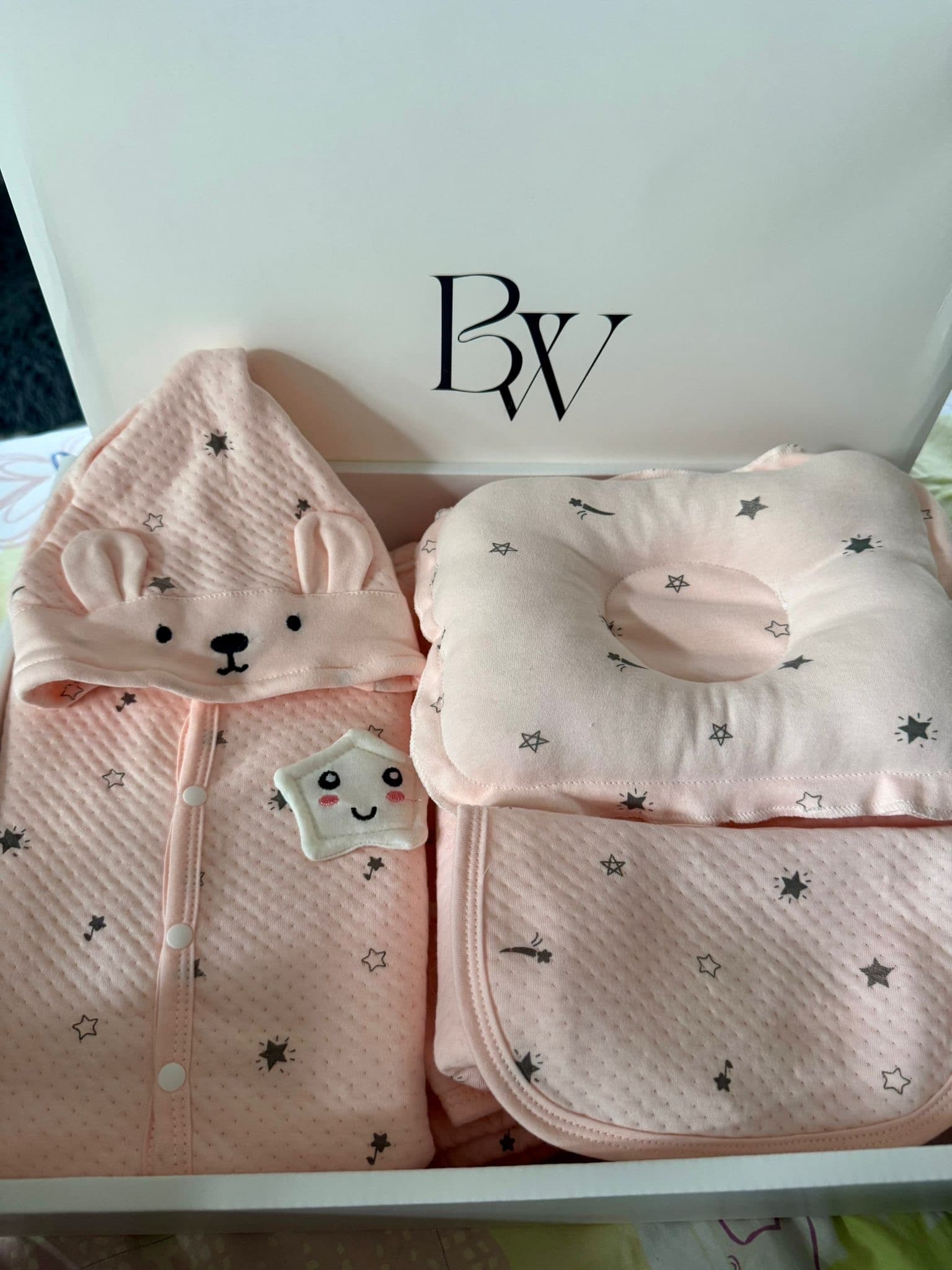 Opened Babywonders UK baby gift set with baby clothing, pillow and blanket in soft pink tones