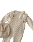 Close-up of beige baby knitted overall outfit with ribbed texture and matching beret hat