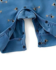 Bottom snap button closure detail on blue puppy print baby romper for easy diaper changing.
