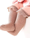 Infant wearing brown lace knit baby socks with scalloped ruffle edge – stylish and cozy fit.