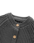 Close-up of charcoal knit baby romper neckline with wooden buttons and ribbed texture