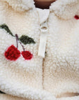 Close-up of cherry embroidery and zipper detail on fluffy baby fleece romper