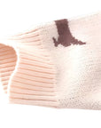Close-up of cream knitted baby romper sleeve showing soft ribbed cuff and brown dog pattern texture