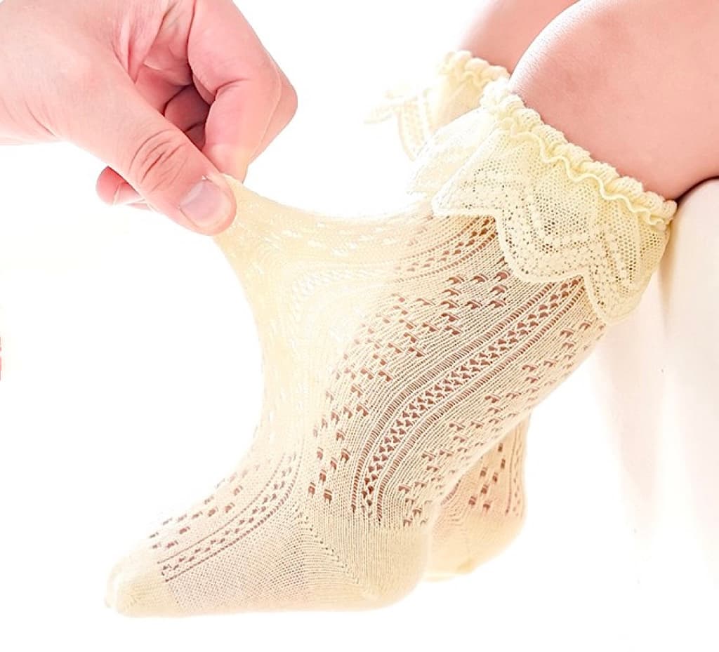 Stretch test of cream lace knit baby socks showing soft, stretchy cotton and breathable design.