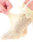 Stretch test of cream lace knit baby socks showing soft, stretchy cotton and breathable design.