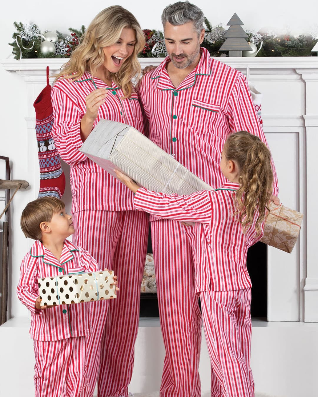 Family in red striped matching Christmas pajamas exchanging gifts