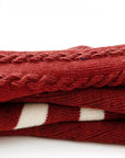 Close-up of folded red baby socks showing knit cotton texture and festive stripe detail.