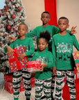 Children wearing matching green Merry Christmas pajamas with festive reindeer design