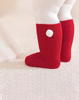 Red baby socks with cute white pom pom detail, soft and stretchy design ideal for newborn winter wear.