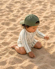 toddler wearing green striped rash guard swim set playing on sandy beach UV protection swimwear