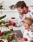 Dad and son in matching Santa print Christmas pajamas decorating Christmas tree together.