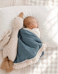 Newborn baby sleeping with a turquoise cotton baby blanket, soft breathable nursery blanket for naps, swaddling and everyday comfort.