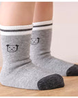 Lifestyle display of patterned cotton baby socks – grey, cream and yellow mix