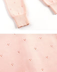 Detailed view of ribbed cuffs and soft textured cotton knit fabric on pink baby jumpsuit.