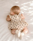 Baby wearing polka dot bubble romper with white scallop trim ribbed baby socks