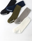 Four pairs of kids' socks in black, green, gray, and white on a white background.