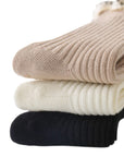 Stack of baby ruffle cotton socks in beige, white, and black colors
