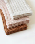 Close-up view of soft ribbed baby socks in beige, pink, and brown showing knit texture
