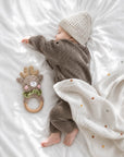 Sleeping newborn baby wrapped in a spotted baby blanket beside a crochet deer teether, a thoughtful baby shower gift and newborn essential in the UK.