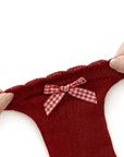 Close-up of soft stretchy red baby sock with checkered bow, seamless and skin-friendly fabric.
