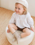 Toddler wearing beige cotton ruffle socks, matching neutral fall outfit