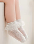 Toddler sitting with cute lace bow socks in soft white cotton