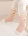 Pink socks with cartoon designs worn by a child on a light background