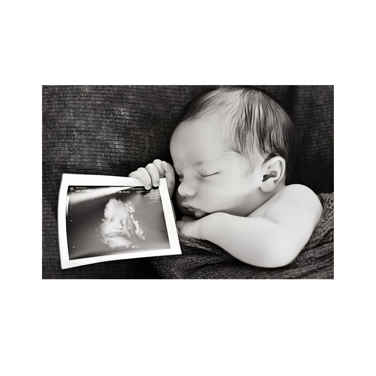 Newborn baby holding ultrasound photo, sentimental keepsake and personalized baby gift idea.