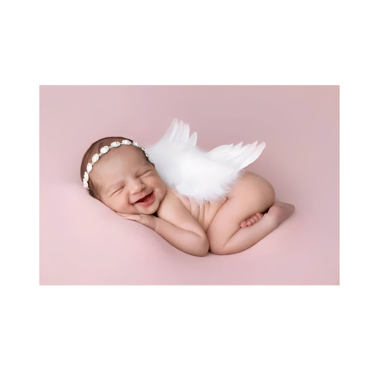 Newborn baby dressed as a tiny angel, peacefully smiling on a pink background — symbolising innocence, love, and new beginnings.