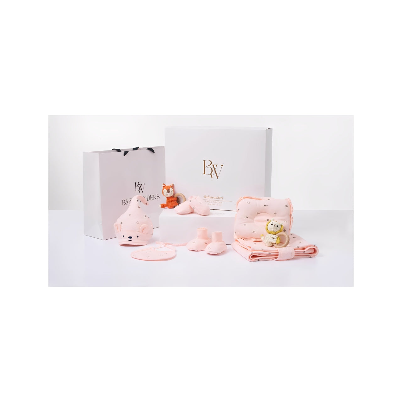 Developmental baby gift set in soft pink hues, with sensory-friendly items like plush animals, baby booties, and a muslin wrap—ideal for supporting early milestones.