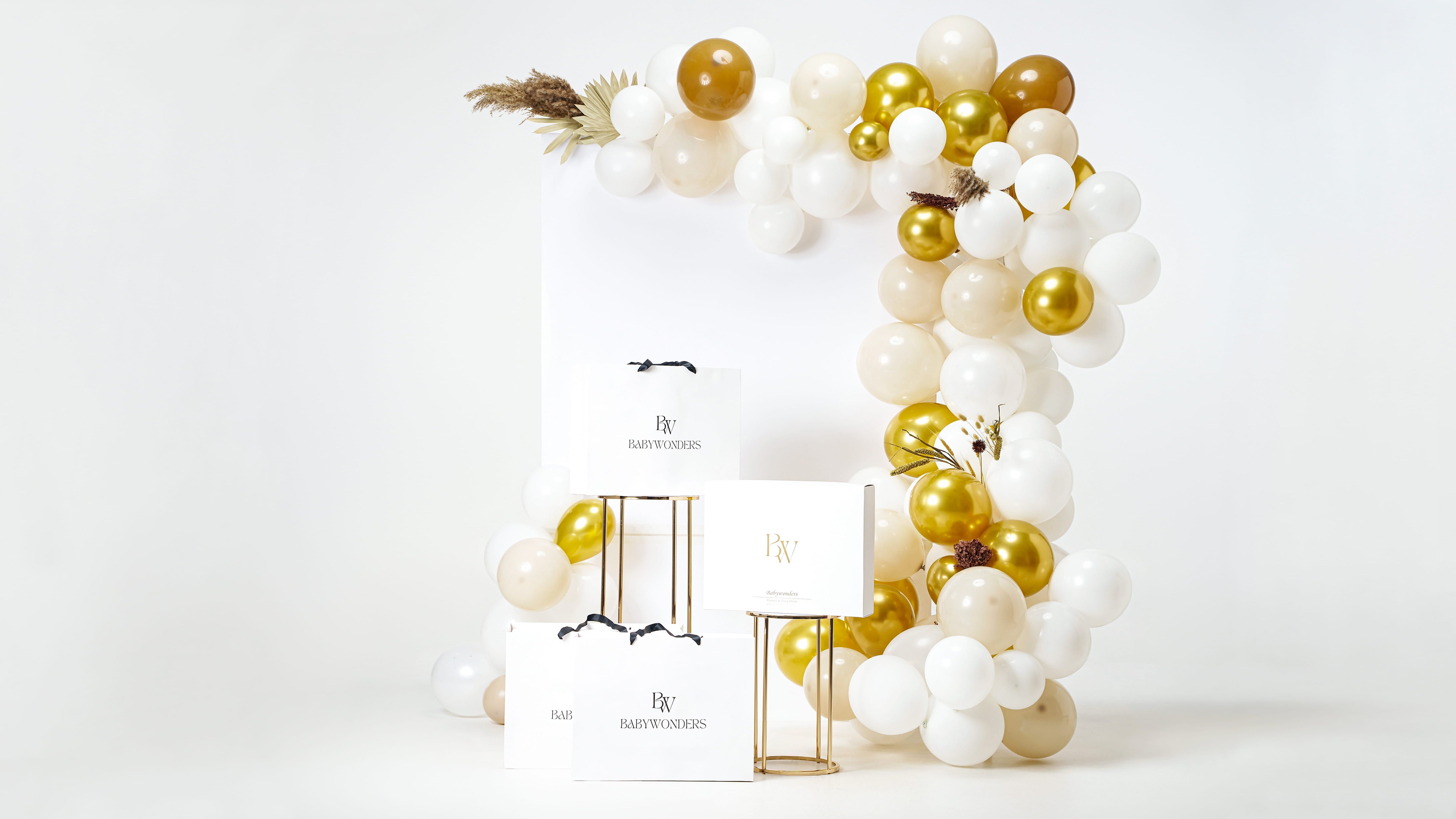 Luxury BabyWondersUK seasonal gift boxes showcased under a festive white and gold balloon arch—perfect for baby showers, seasonal gifts, or milestone celebrations.