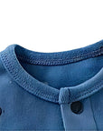 Close-up of the neckline stitching and button design on blue puppy print baby romper.