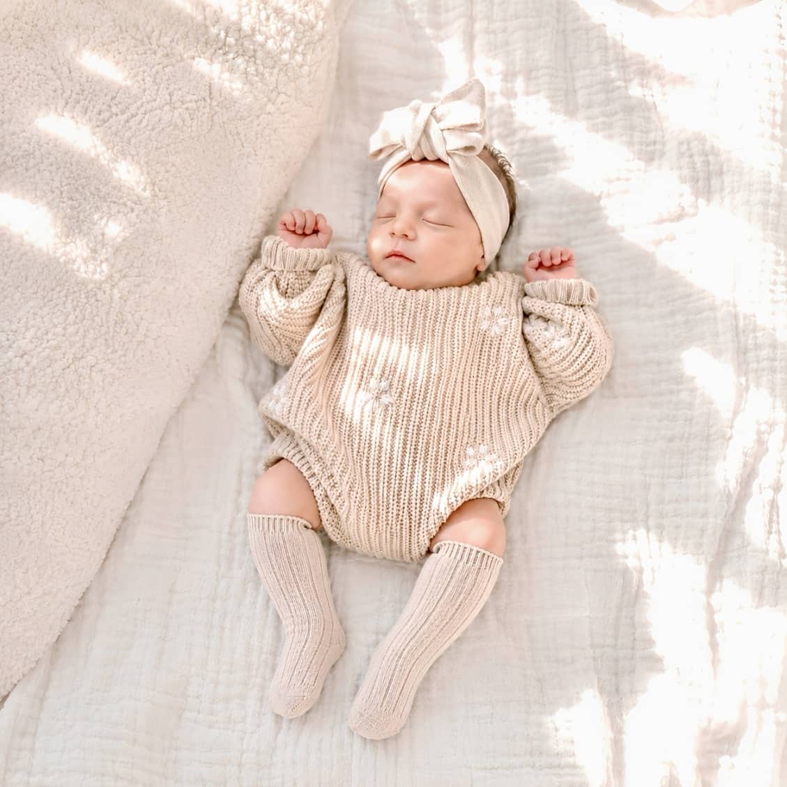 Baby wearing ribbed knit knee-high baby socks in soft cotton with cosy neutral newborn outfit and minimalist nursery style