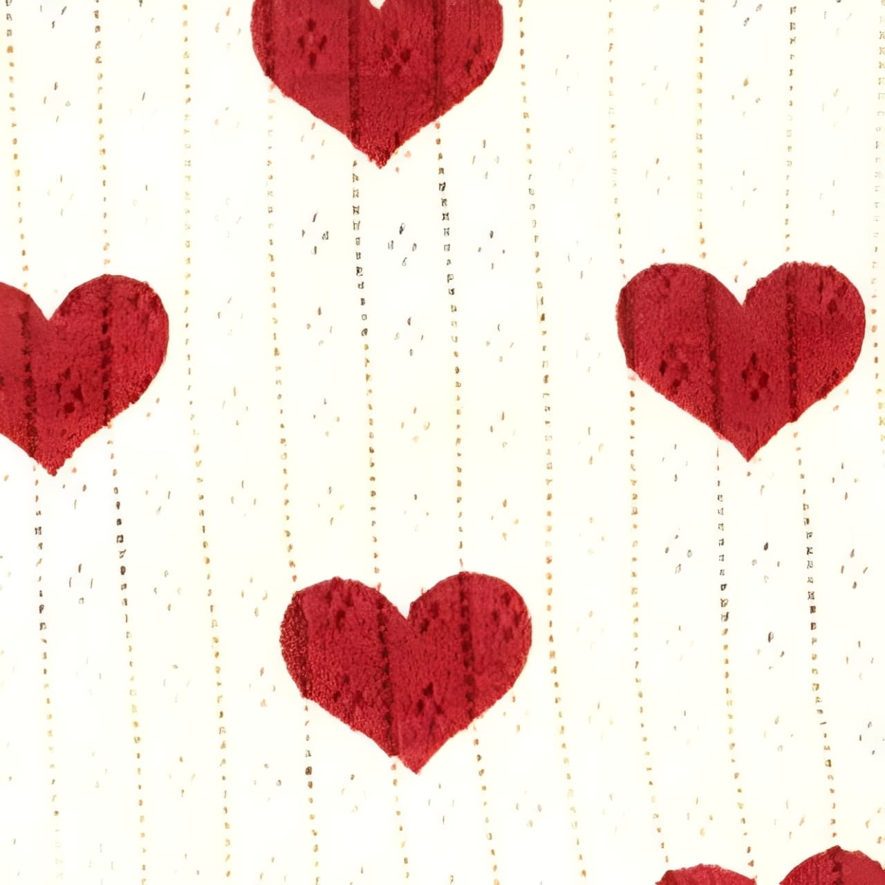 Detailed close-up of cream ribbed cotton fabric featuring red heart pattern, showing soft breathable knit texture.