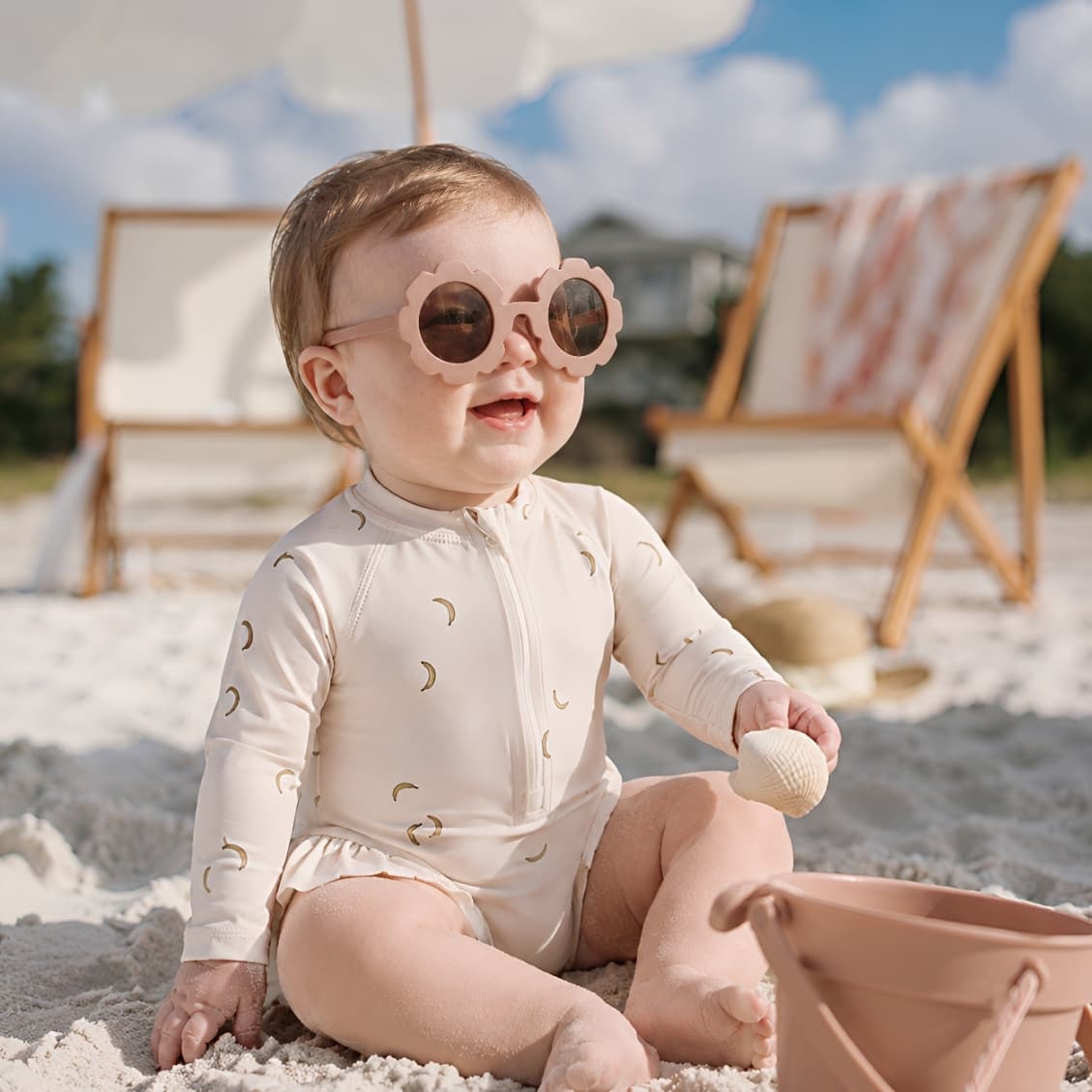 baby girl wearing banana print long sleeve swimsuit walking on the beach