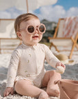 baby girl wearing banana print long sleeve swimsuit walking on the beach