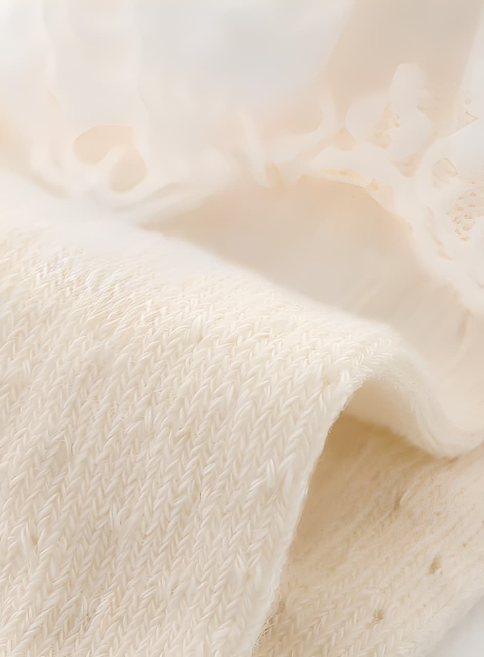 Close-up of soft cotton knit fabric from baby lace socks, showing fine breathable texture
