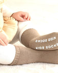 Baby sitting wearing soft brown cotton anti-slip socks for cozy warmth