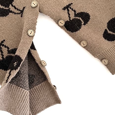 Detailed view of button design and inside stitching on baby cherry knit romper.
